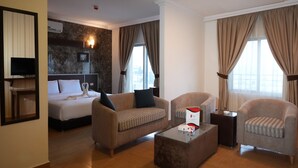 Una habitación de hotel con una cama, dos sillones, una mesa de centro, un televisor y una chimenea.
