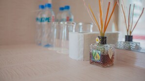 A table with a glass bottle of reed diffuser, a glass bottle of water, and a glass of water. - Jasmine House @ Pattaya (Pattaya)