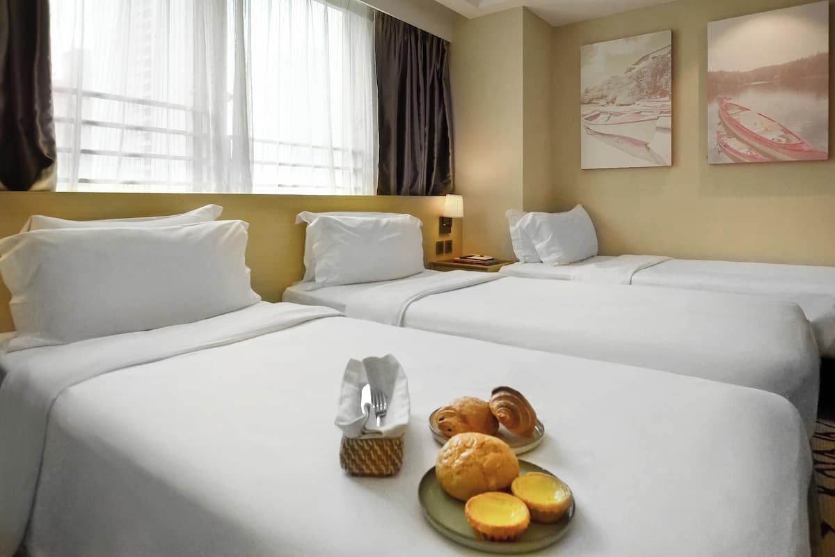 A hotel room with two beds, a window with sheer curtains, and artwork on the wall.