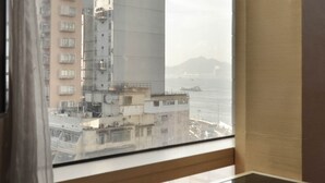 A view from a window overlooking a cityscape with buildings and a body of water.