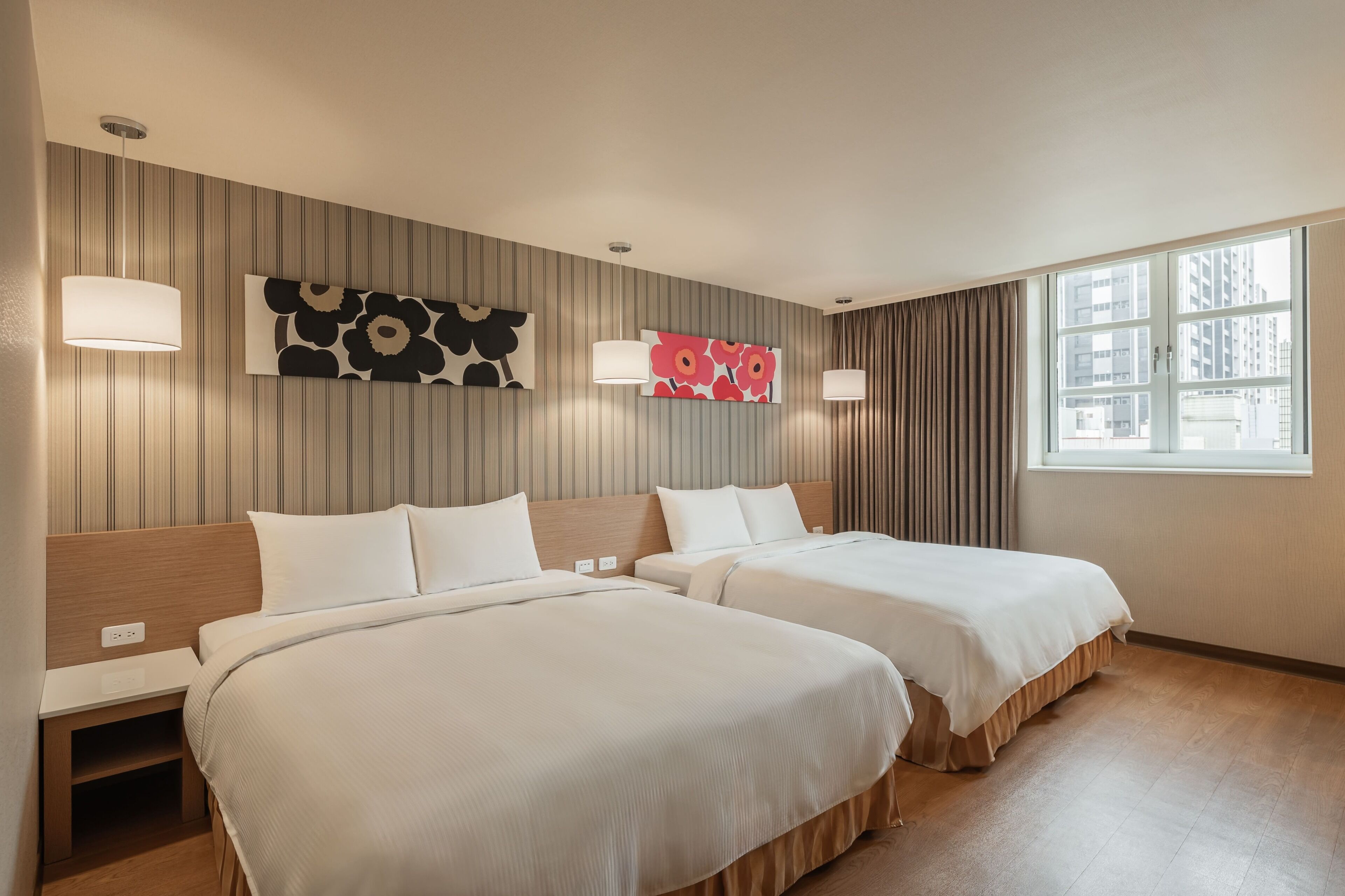 Een hotelkamer met twee bedden, een groot raam en twee wandlampen.