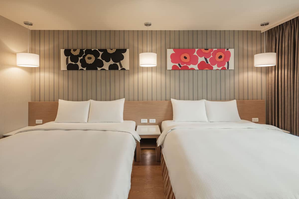 Une chambre d’hôtel avec deux lits, une tête de lit en bois, un mur à rayures et deux lampes fixées au mur.