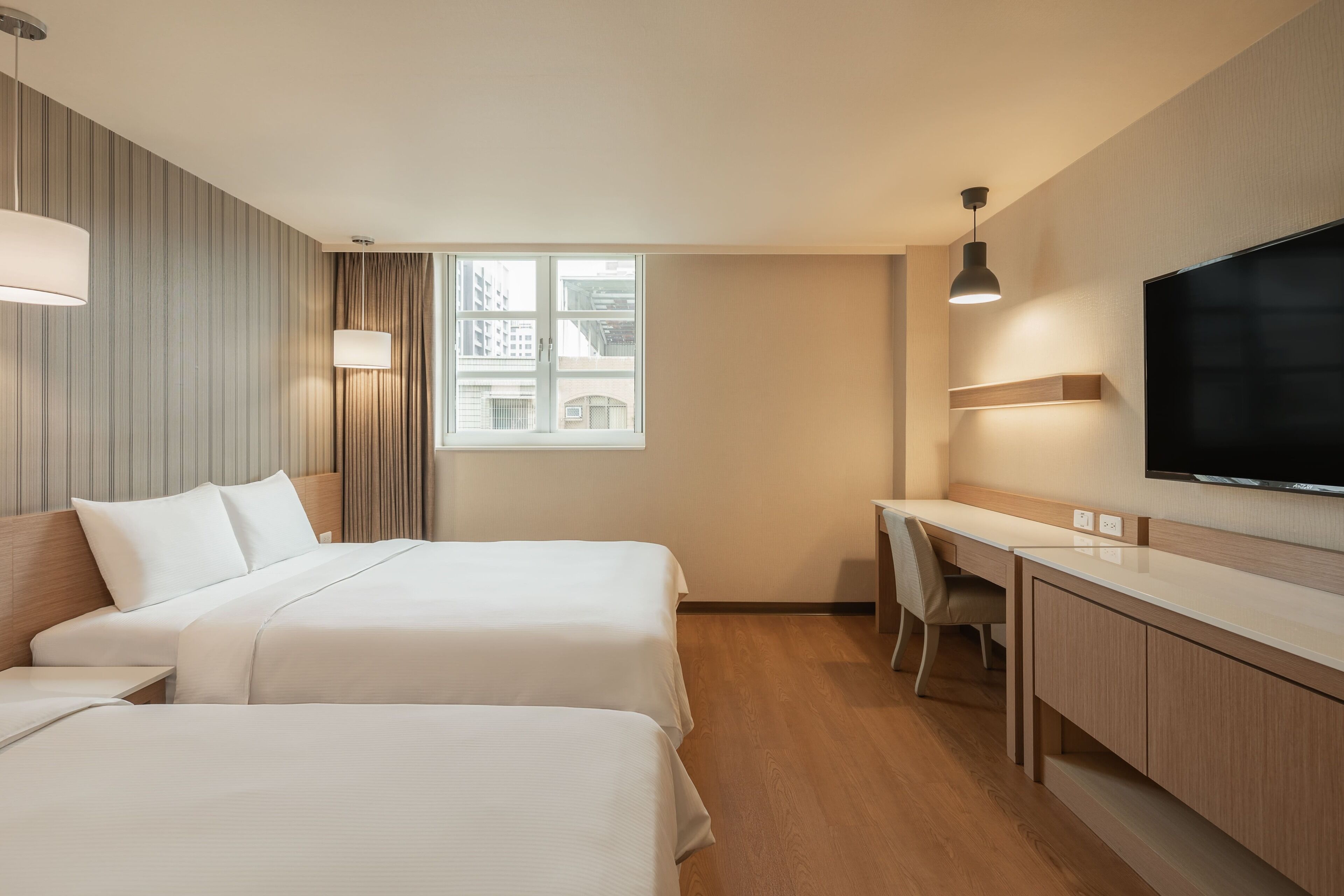 Een hotelkamer met twee bedden, een bureau, een stoel, een televisie en een raam met gordijnen.