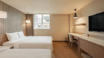 Een hotelkamer met twee bedden, een bureau, een stoel, een televisie en een raam met gordijnen.