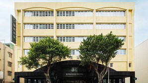 Un immeuble à plusieurs étages, avec une enseigne indiquant « HÔTEL DE LA BIENVÉILLANCE » à l’entrée.