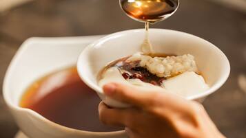 A hand holding a bowl with a beverage being poured into it.