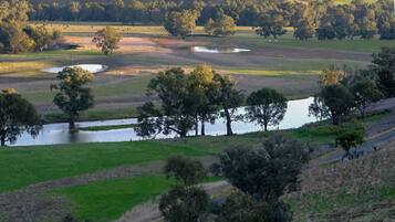 A panoramic view of a countryside landscape with rolling hills, a river, and scattered trees.