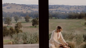 A person sitting on a wooden deck with a scenic view of rolling hills and trees.