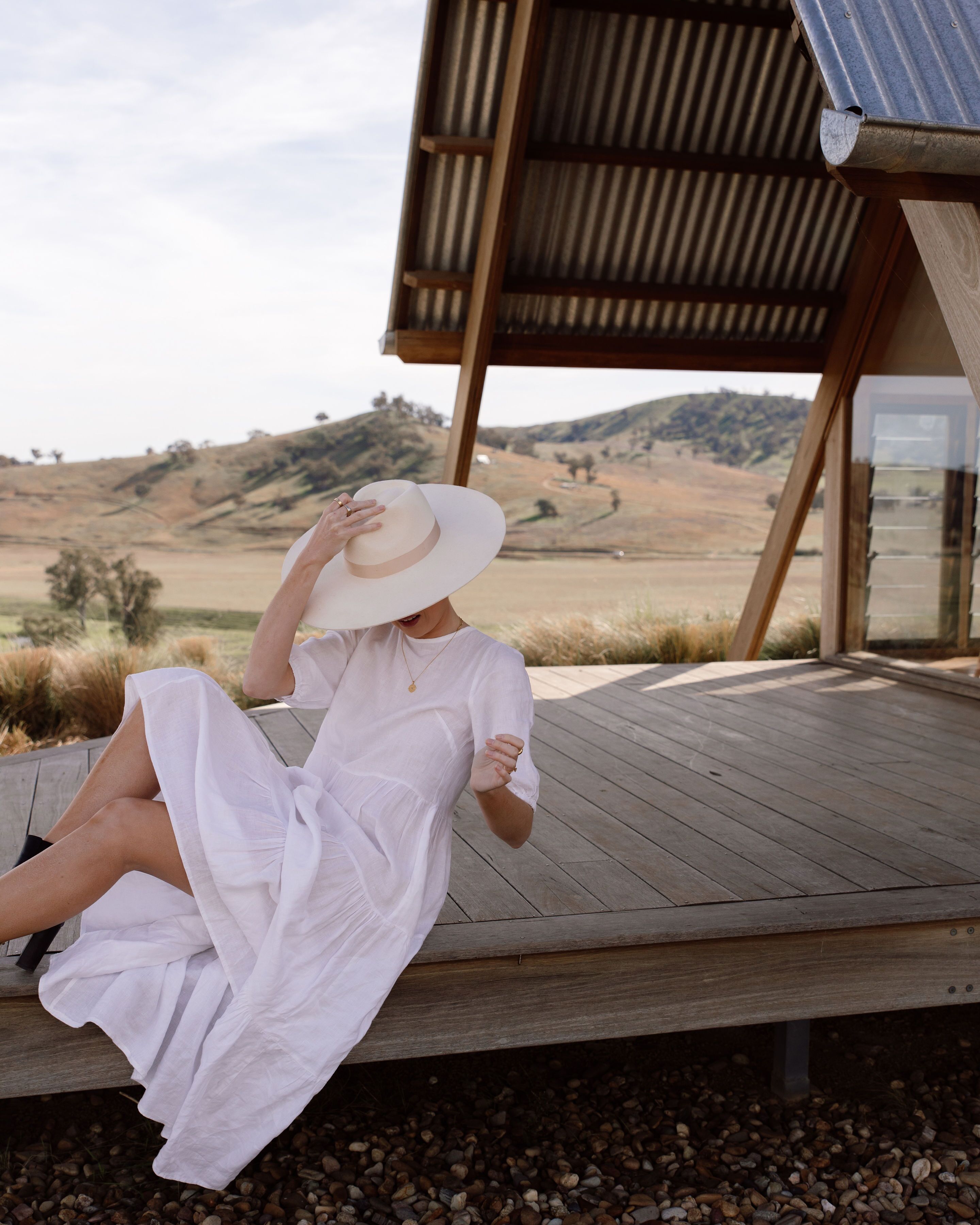 A person sitting on a wooden deck with a view of a hilly landscape.