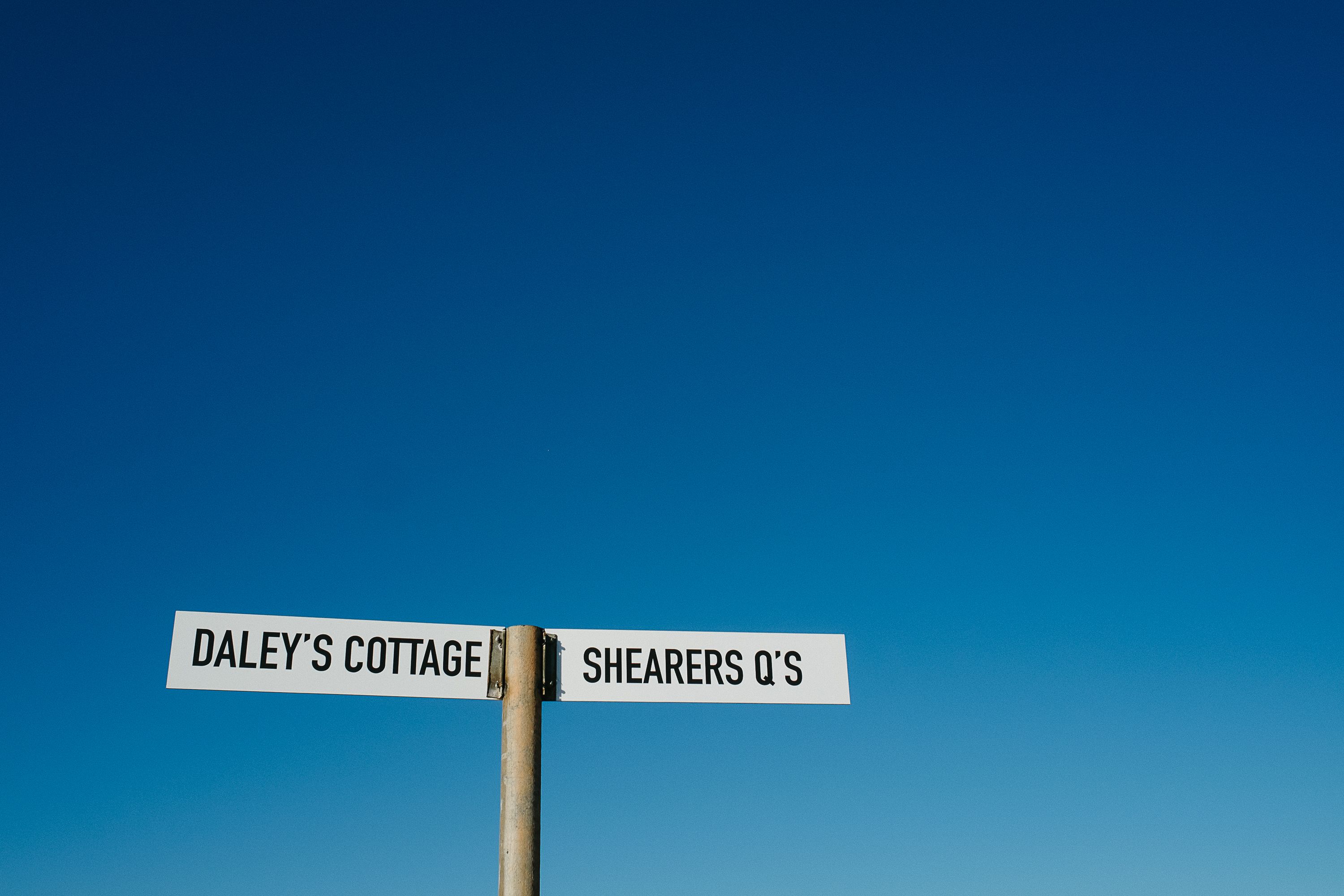 Ein Straßenschild mit der Aufschrift 'Daley's Cottage' und 'Shearers Q's'.