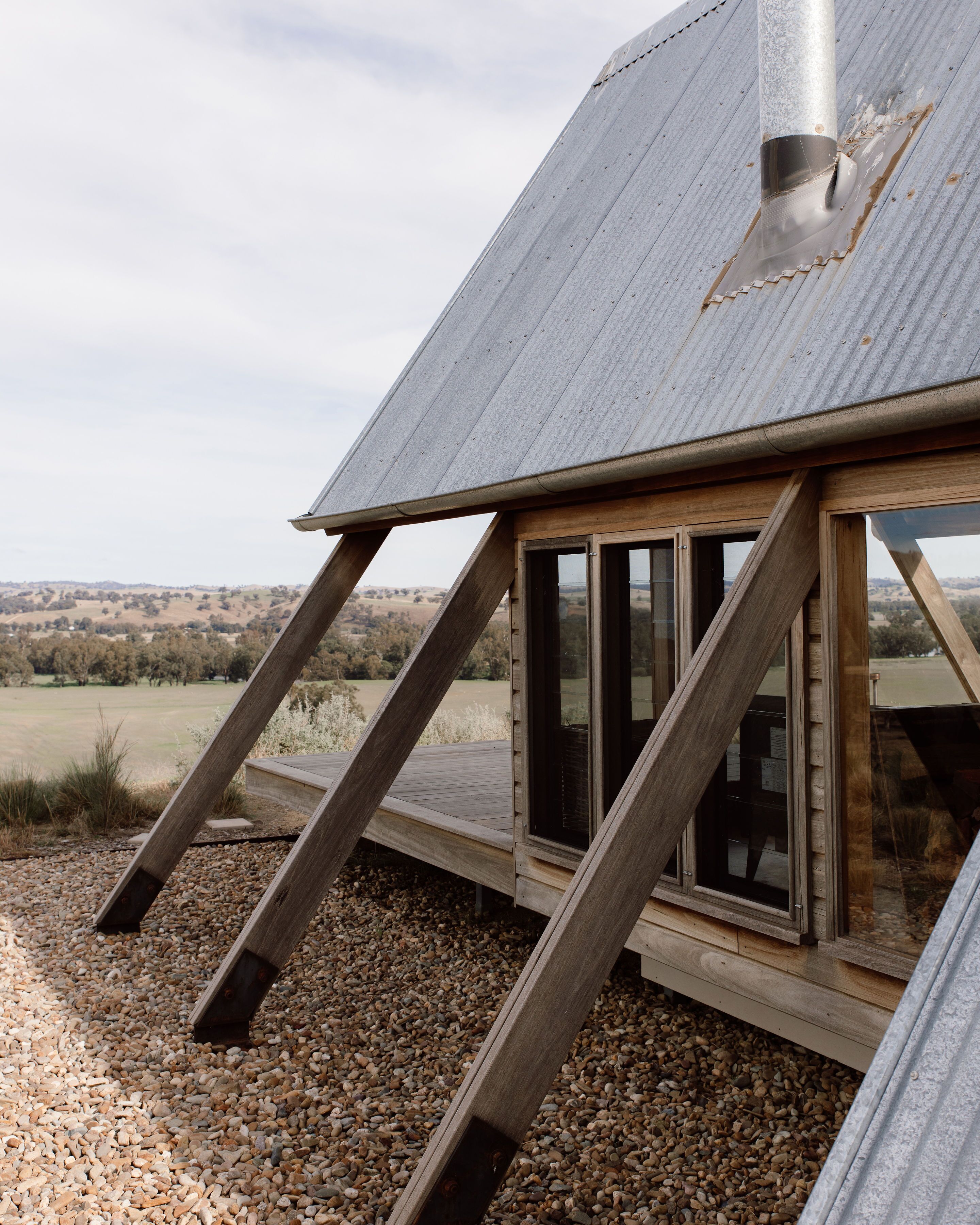 Una casa moderna con techo inclinado, ventanas amplias y una terraza de madera.