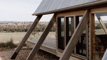 Una casa moderna con techo inclinado, ventanas amplias y una terraza de madera.