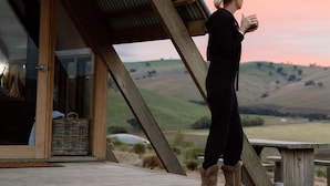 A person standing on a wooden deck with a view of rolling hills and a sunset. - Kimo Estate (Nangus)