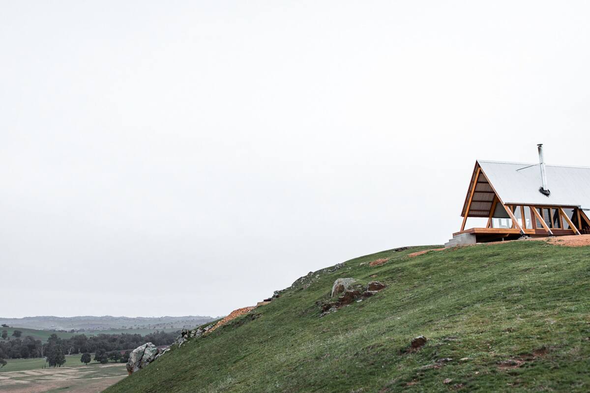 A modern house on a grassy hill with a sloped roof and large windows.