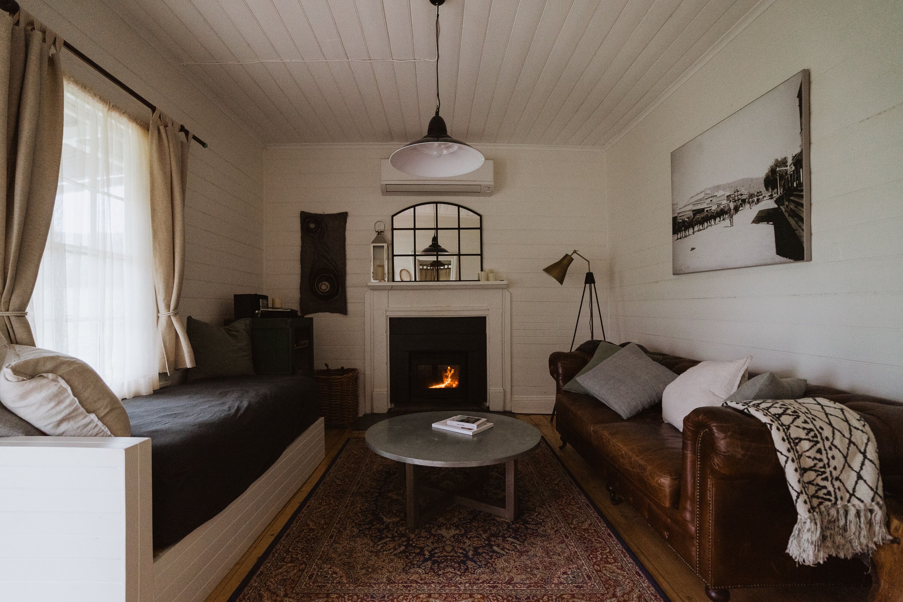 Un salón acogedor con chimenea, un sofá, una mesa de centro y un cuadro en la pared.