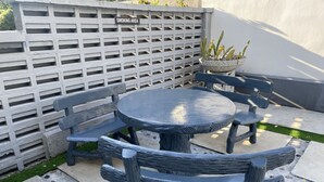 A patio area with a round table and four wooden chairs, a concrete wall with a 'SMOKING AREA' sign, and a planter with plants. - The Six Residences at JB Sentosa (Johor Bahru)