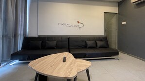 A modern living room with a black sofa, a wooden coffee table, and a wall with a motivational quote. - The Six Residences at JB Sentosa (Johor Bahru)