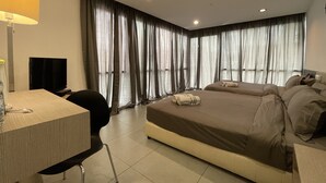 A hotel room with a bed, a desk, a chair, a TV, and curtains. - The Six Residences at JB Sentosa (Johor Bahru)