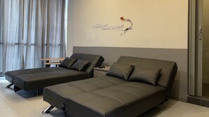 A modern room with two dark sofas, a small wooden table, and a wall with a motivational quote. - The Six Residences at JB Sentosa (Johor Bahru)