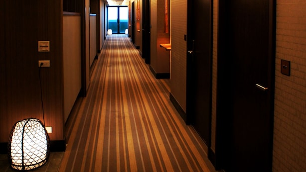 A hotel hallway with striped carpet, multiple doors, and a security camera on the ceiling. - FORTUNE INN (Taipei)
