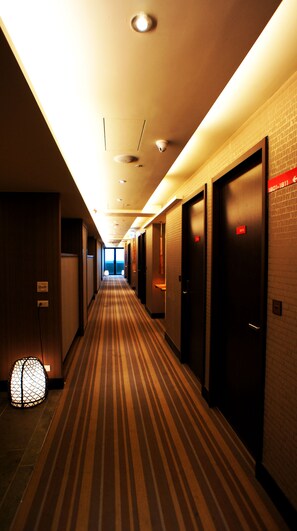 A hotel hallway with striped carpet, multiple doors, and a security camera on the ceiling. - FORTUNE INN (Taipei)