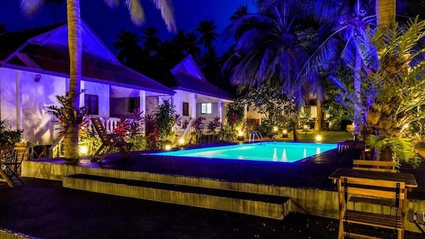 A pool area with steps leading up to it, surrounded by palm trees and plants. - Fullmoon House Samui (Koh Samui)