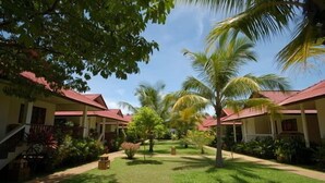 A resort with multiple buildings, each with a red roof and surrounded by lush greenery and palm trees. - Fullmoon House Samui (Koh Samui)