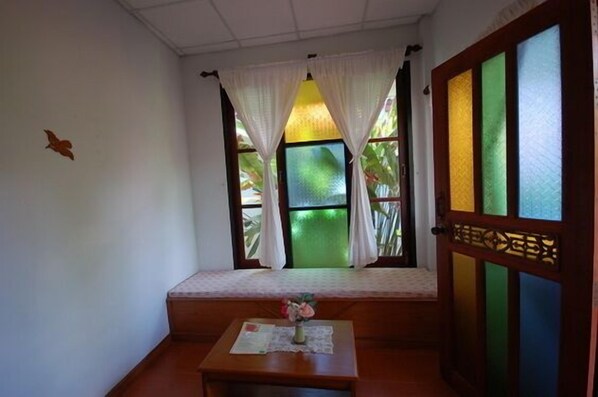 A room with a window, a bench, and a table with a vase.