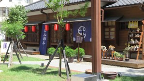 A traditional Japanese building with a wooden exterior, a covered porch, and potted plants.