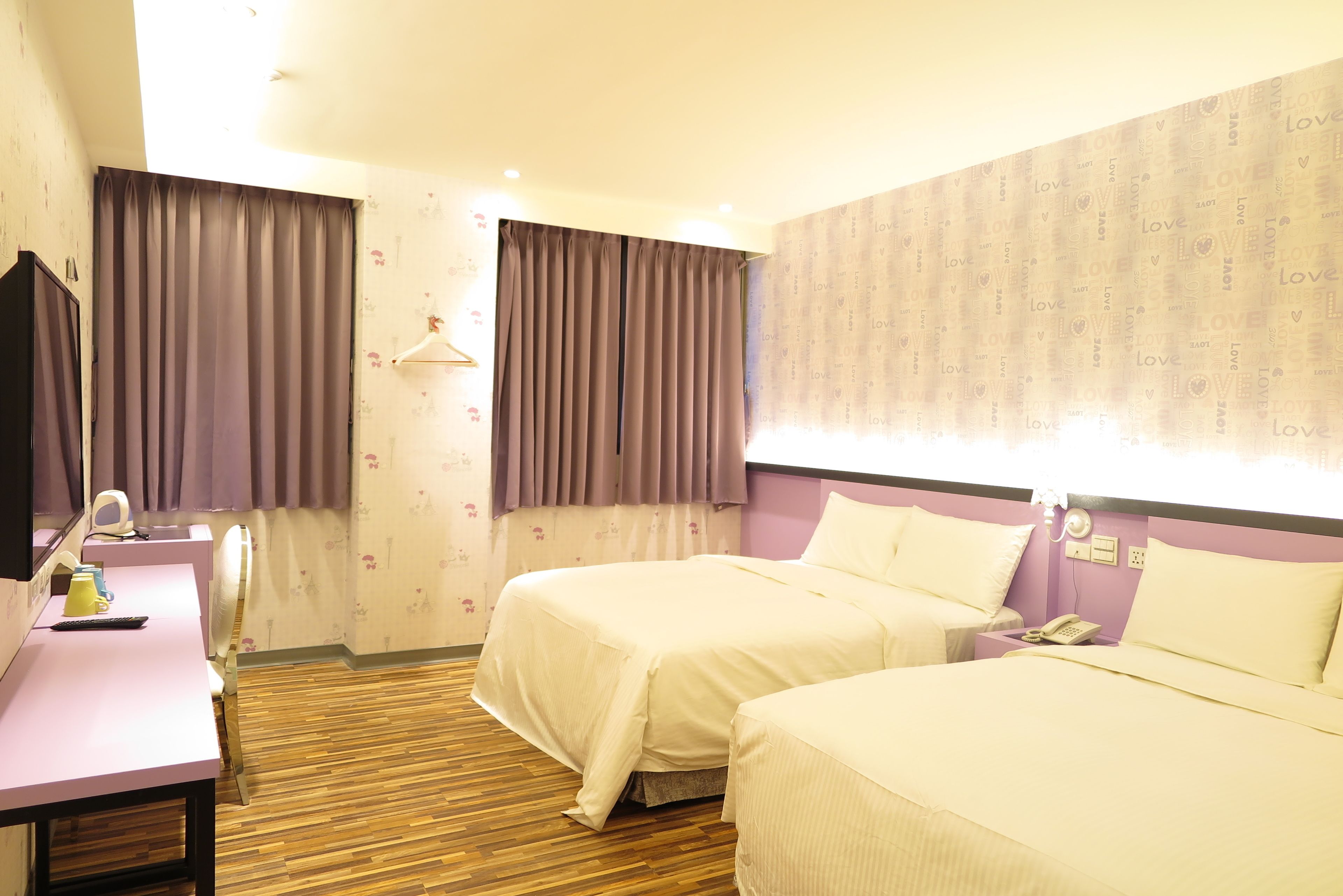Una habitación de hotel con dos camas, un escritorio con computadora, teléfono y espejo.