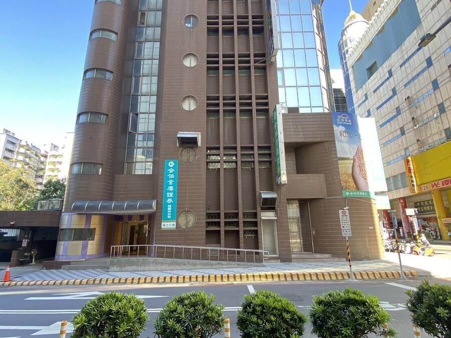 A modern building with a prominent entrance, multiple floors, and a mix of glass and brick facade.
