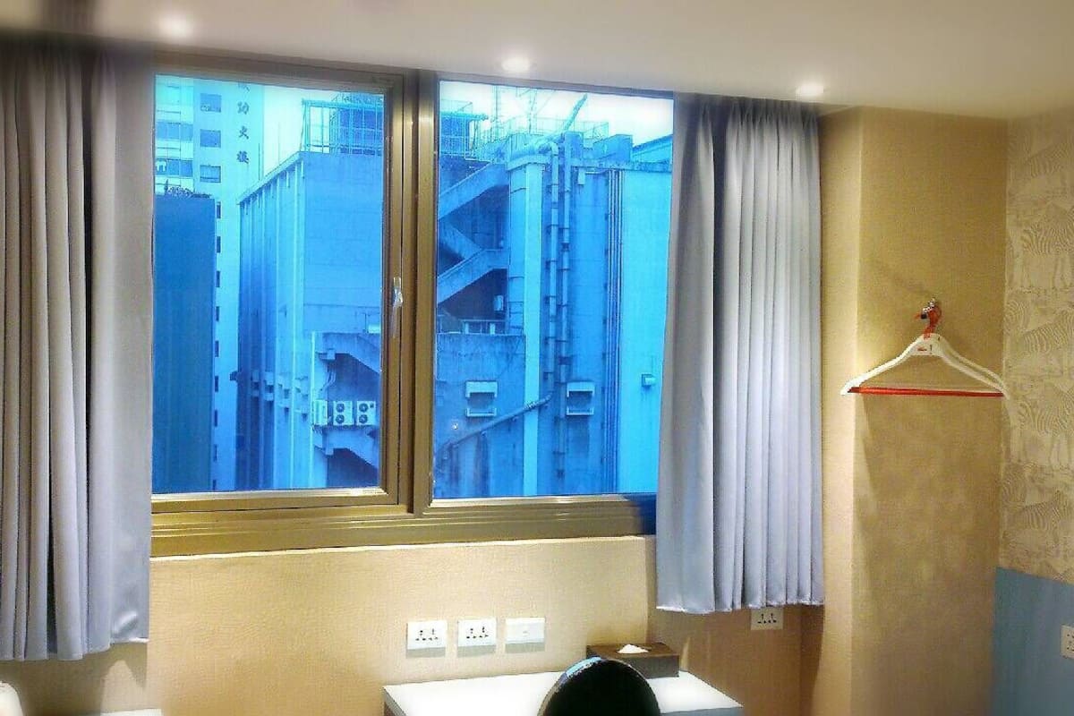A hotel room with a large window, a sink, and a mirror.