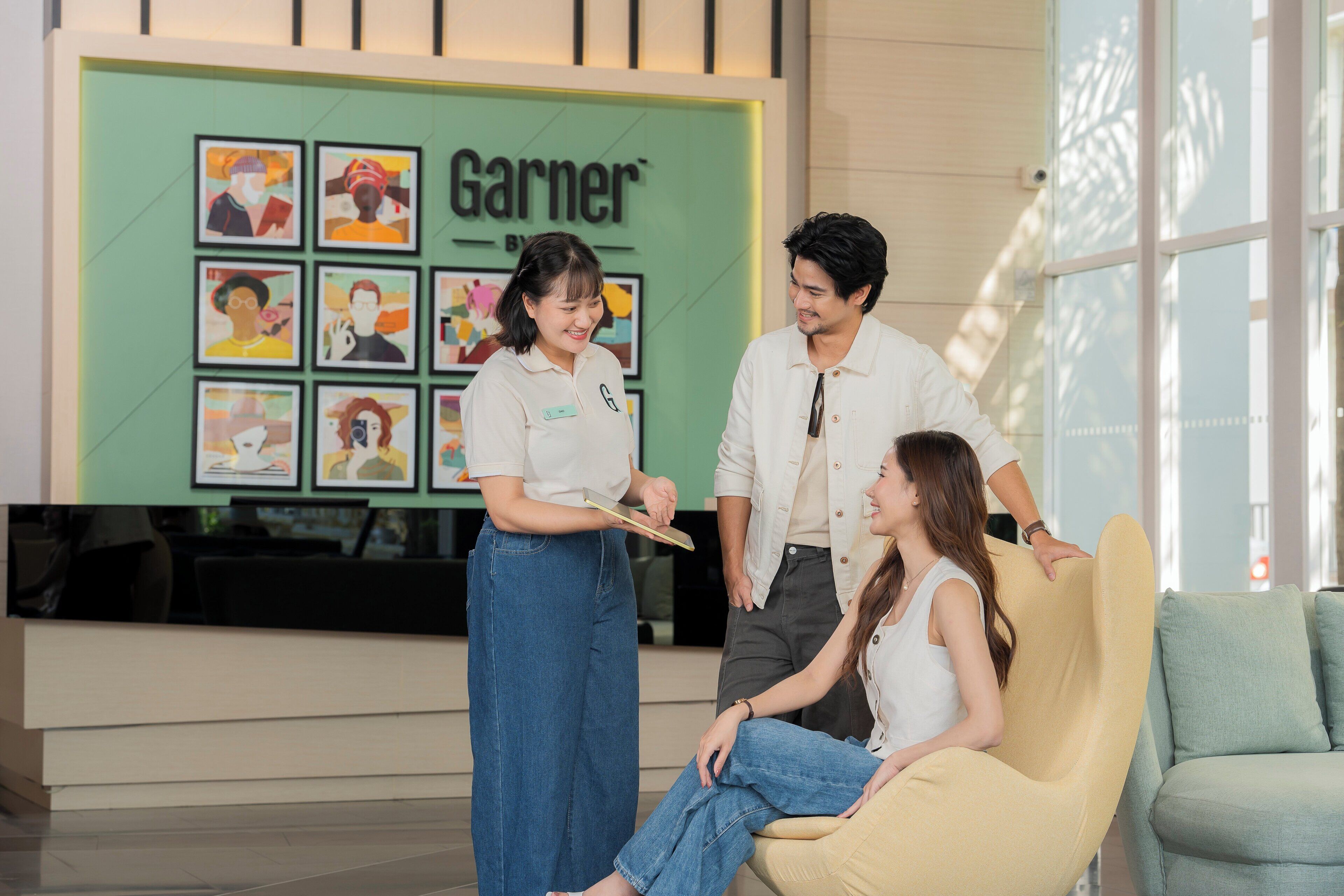 Un espace d’accueil agrémenté du logo Garnier, de tableaux encadrés et d’un coin salon avec un canapé et des fauteuils.
