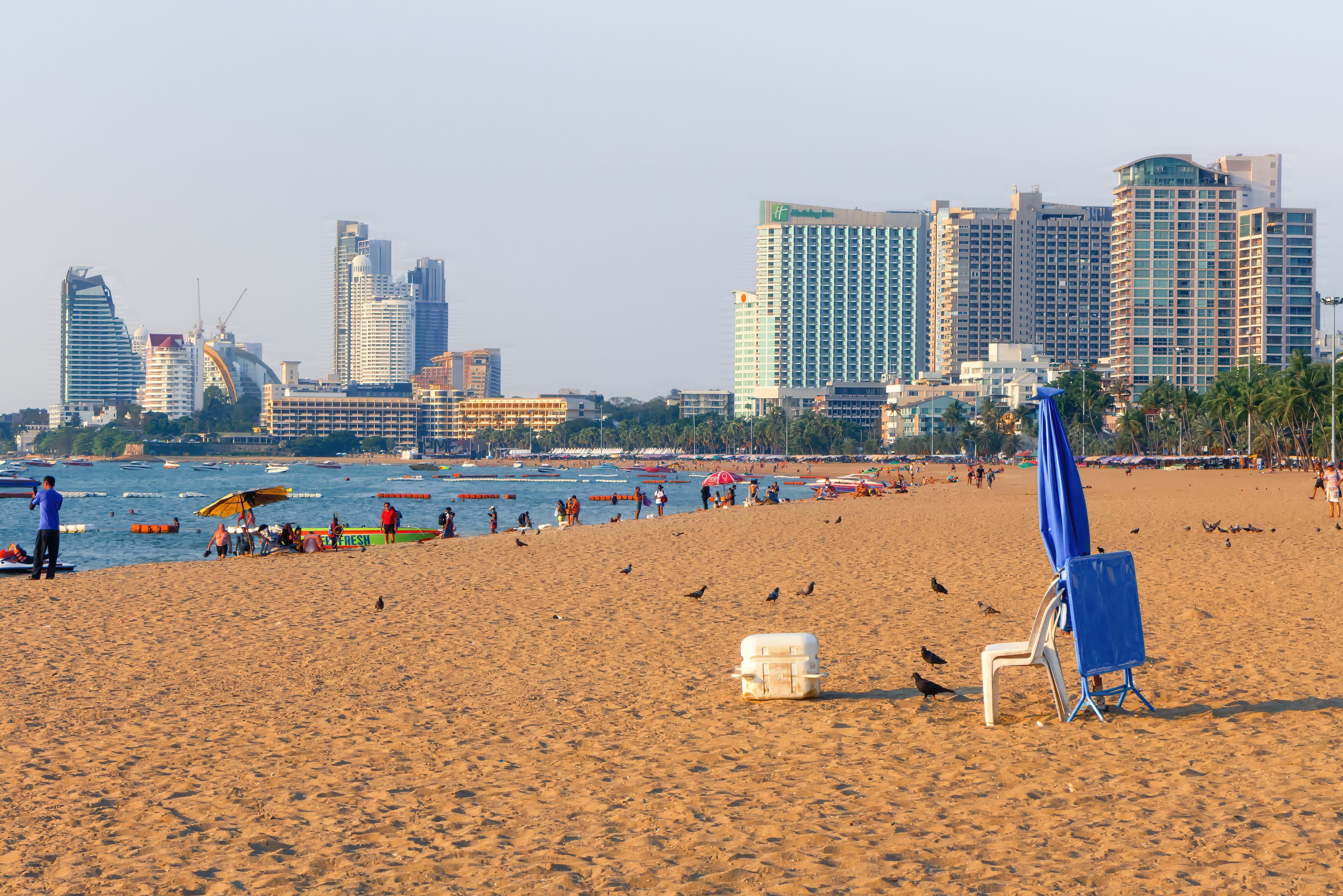 Una playa con el horizonte urbano al fondo, que incluye edificios altos y un edificio curvo característico.