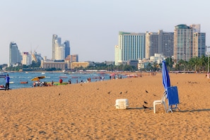 Une plage avec, en arrière-plan, le profil d’une ville, comprenant des immeubles de grande hauteur et un bâtiment à l’architecture courbe remarquable.