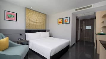 A modern hotel room with a large bed, a bedside table, a chair, and artwork on the walls.