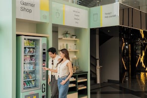 Máquina expendedora con aperitivos y bebidas, un letrero para una tienda Garnier y estantes con productos.