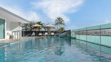 Alberca al aire libre, sombrillas en la alberca y camastros