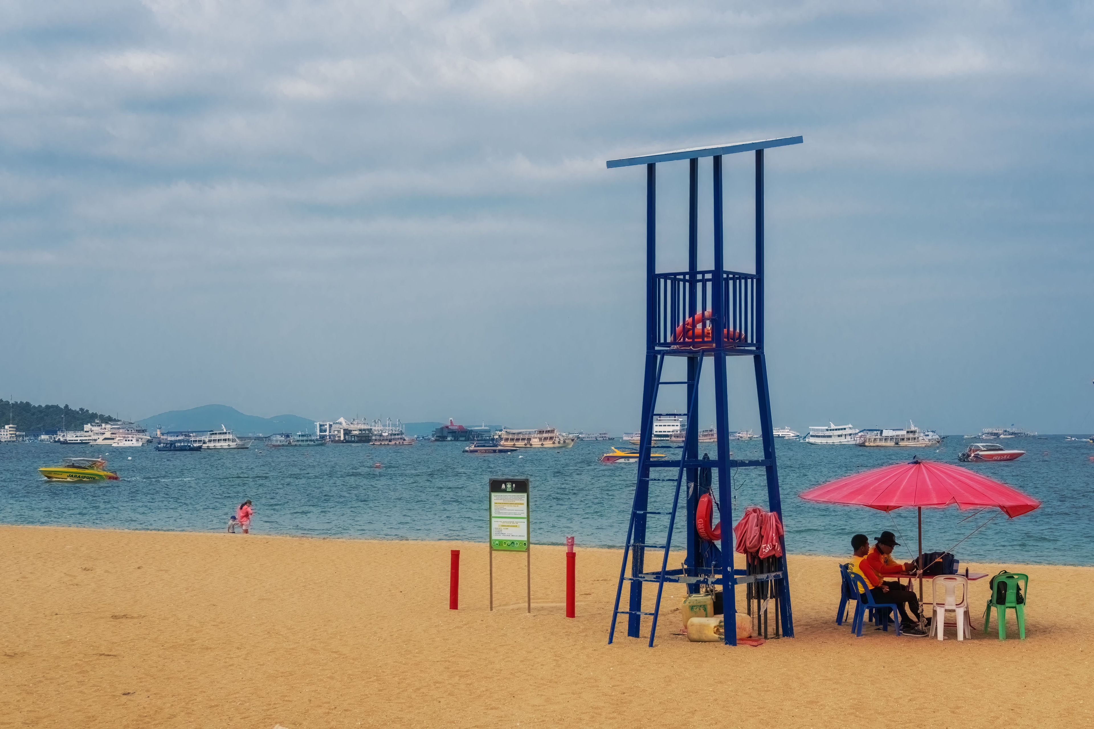 A lifeguard tower on a beach with a clear view of the sea and boats in the background.