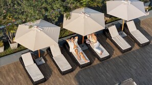 Una piscina al aire libre, sombrillas, sillones reclinables de piscina