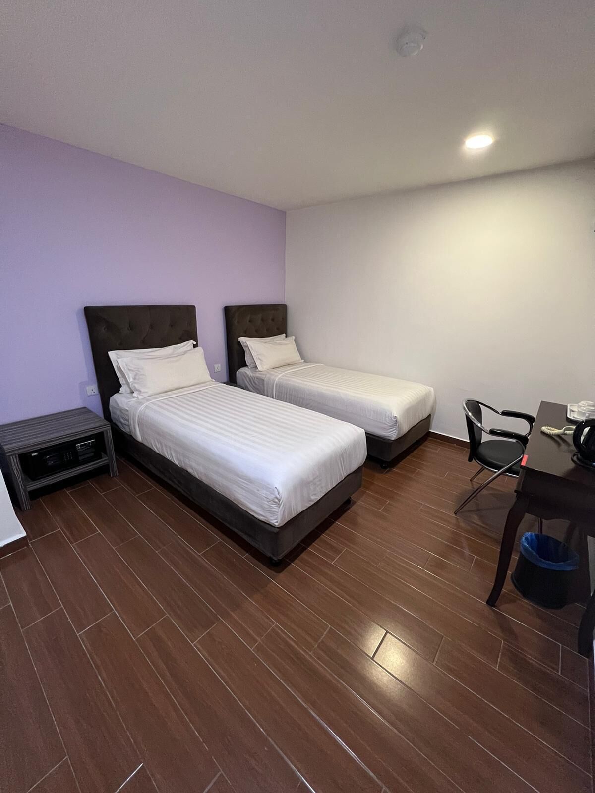 Een hotelkamer met twee bedden, een bureau, een stoel en een tafeltje.