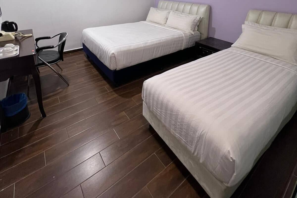 A hotel room with two beds, a desk with a chair, and a small table.