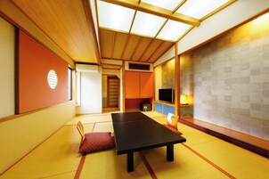 Una habitación con tatami, una mesa baja, un televisor y un puertas correderas.