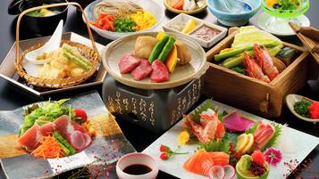 A variety of Japanese dishes including sushi, sashimi, and tempura, arranged on a table with multiple serving dishes and a hot pot.