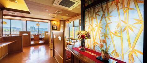 A hotel lobby with a wooden reception desk, a red runner, and a large window with a view of the city.