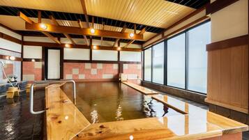 Piscina interior moderna com bancos de madeira e chão ladrilhado.