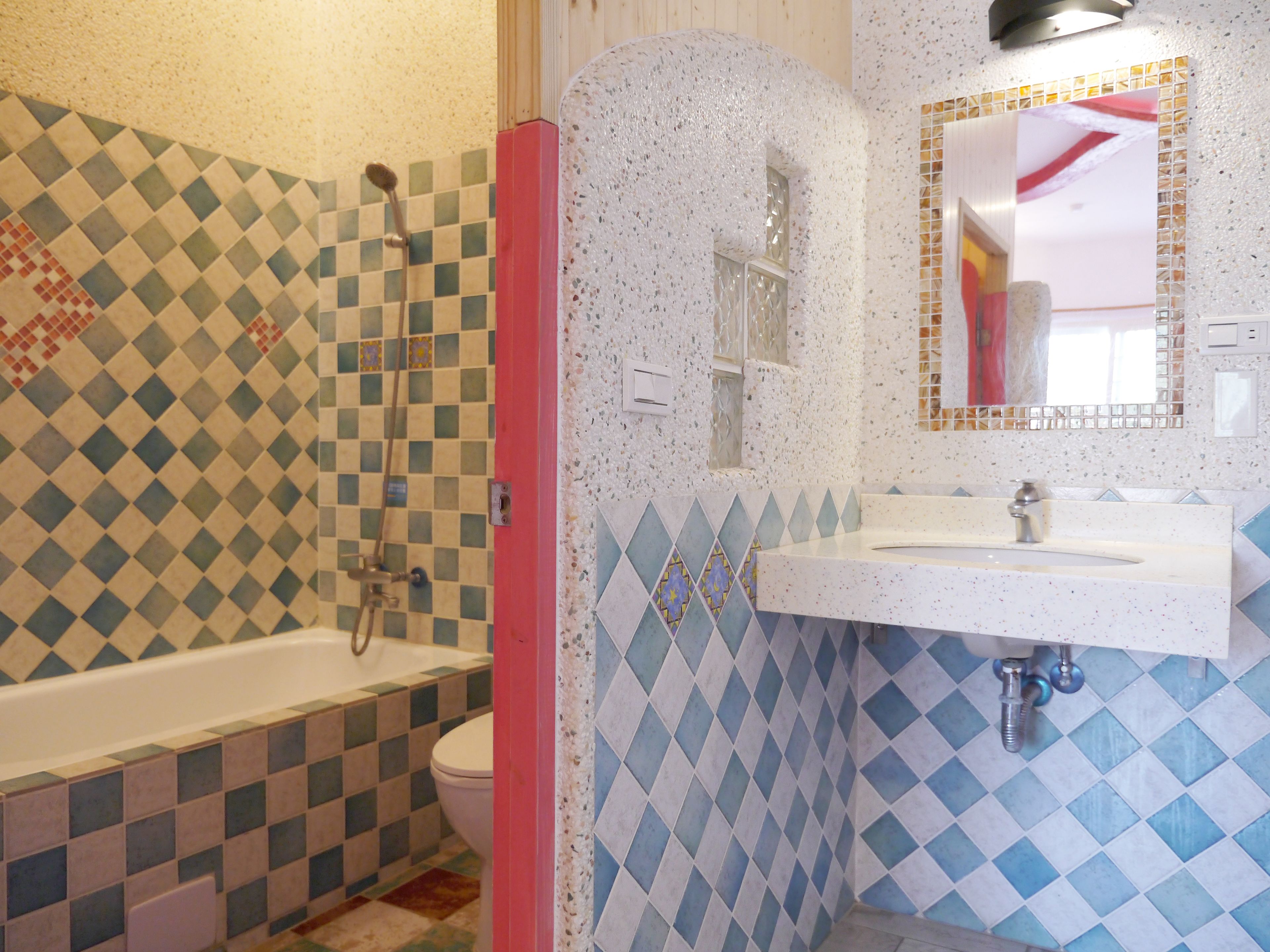 A bathroom with a checkered tile pattern, a bathtub, a toilet, and a sink with a mirror.