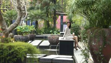 Sit and unwind in a serene garden setting surrounded by lush greenery and a soothing water feature.