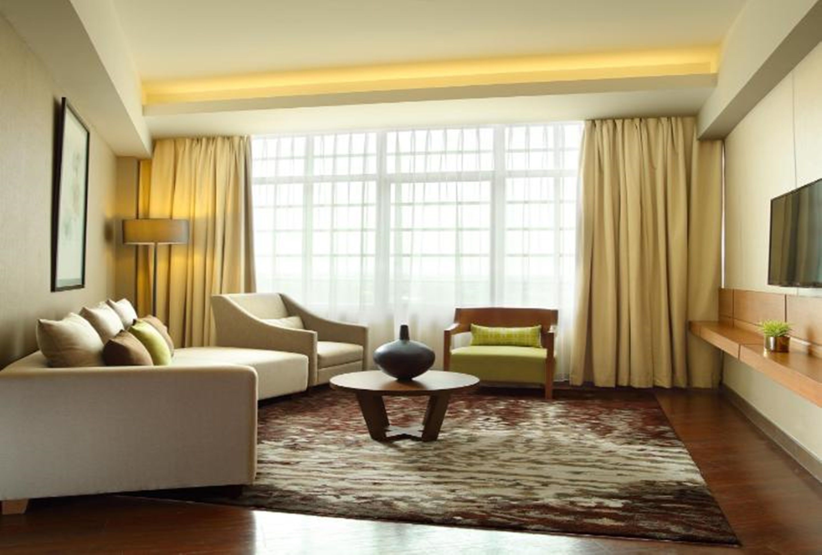 A modern living room with a sofa, armchairs, a coffee table, and a large window with curtains.