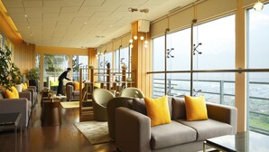 Amplia sala de estar con un ventanal que ofrece vistas de la ciudad. Hay varias opciones de asientos, incluyendo sofás y sillones.